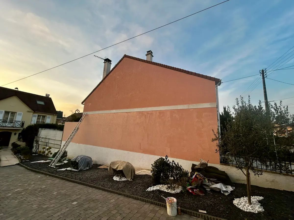 Pignon de maison entièrement enduit en orangé, vu depuis l'allée
